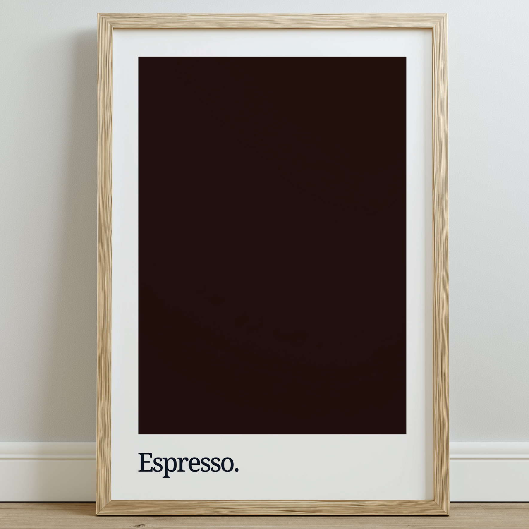 A framed print featuring a dark brown background with the word "Espresso." in white typography at the bottom, displayed against a light wall and wooden floor.