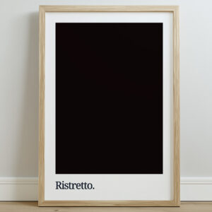 A framed typography print featuring the word "Ristretto" in white against a dark coffee-colored background, displayed on a light wooden floor with a neutral wall behind it.