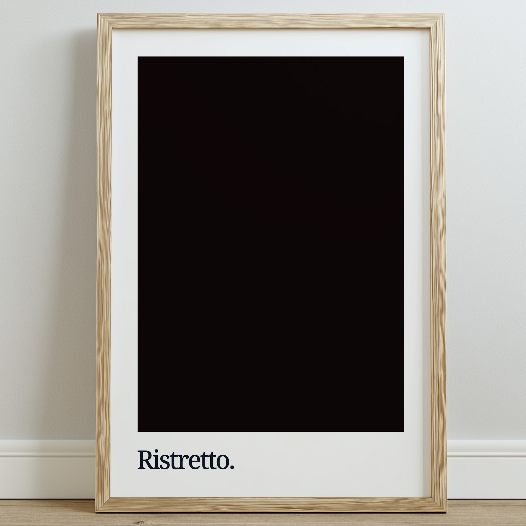 A framed typography print featuring the word "Ristretto" in white against a dark coffee-colored background, displayed on a light wooden floor with a neutral wall behind it.