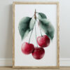 A framed poster print featuring three red cherries hanging from green leaves, set against a white background, with a light wooden frame.